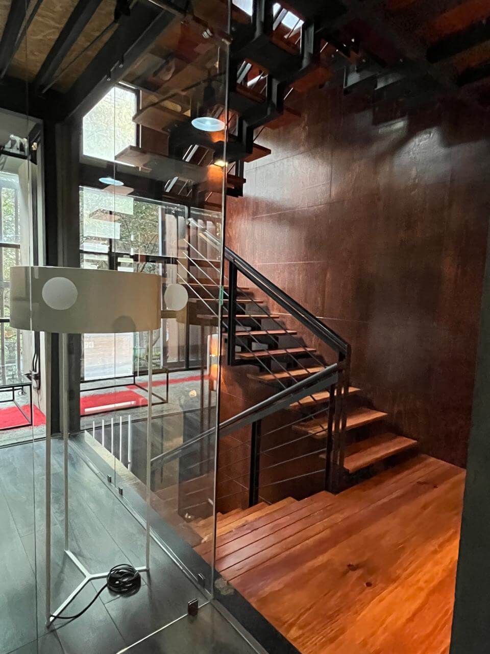 Vista del atrio y escalera principal de las oficinas de ALC, integrando arquitectura abierta y sala de reuniones
